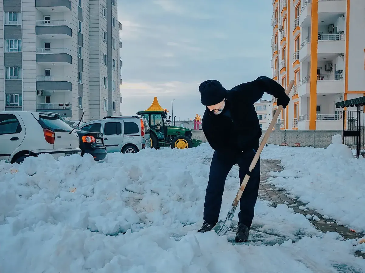 A person clearing a walkway beside apartment buildings