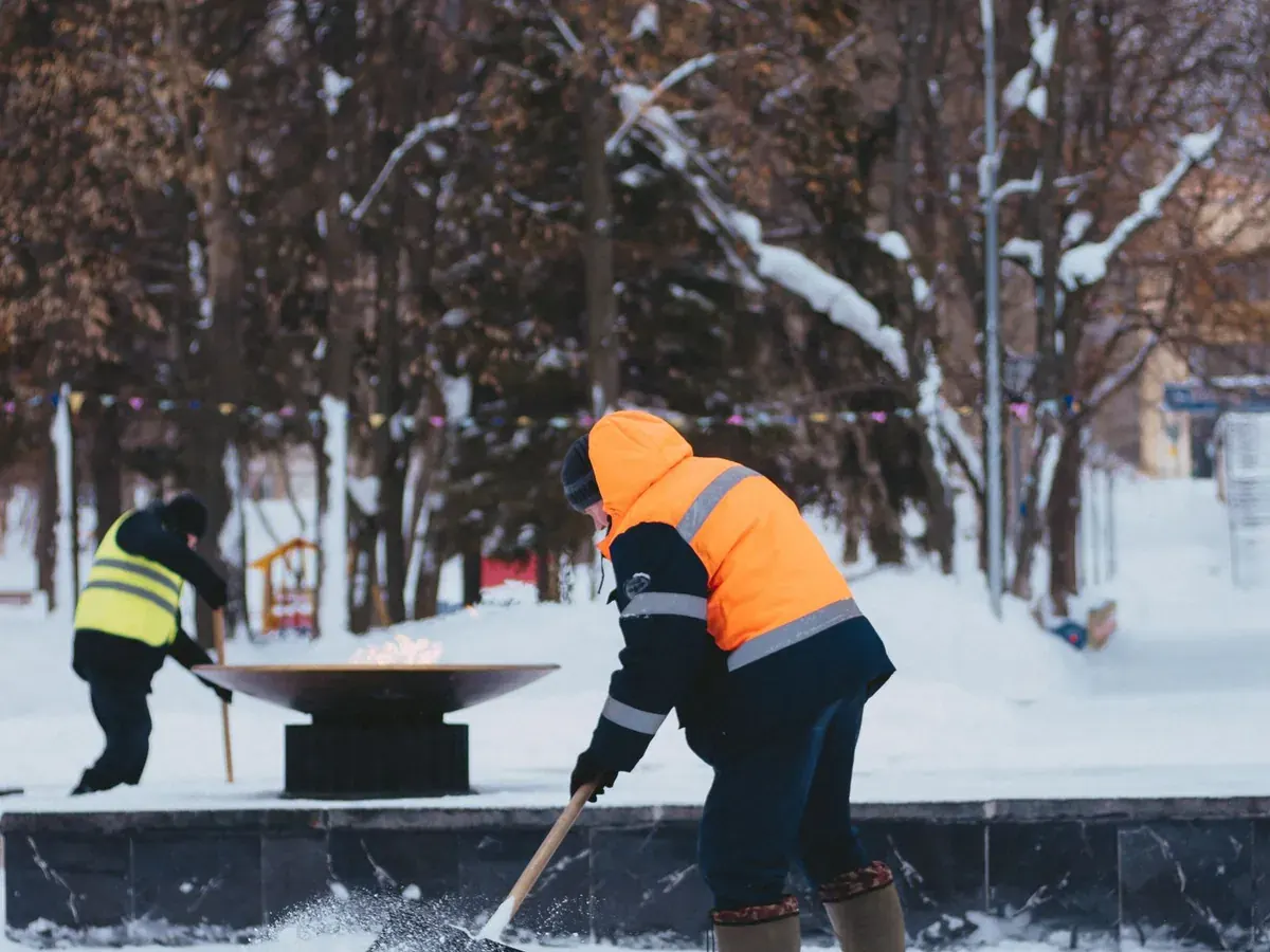Crew in high-visibility vests clearing snow in a park