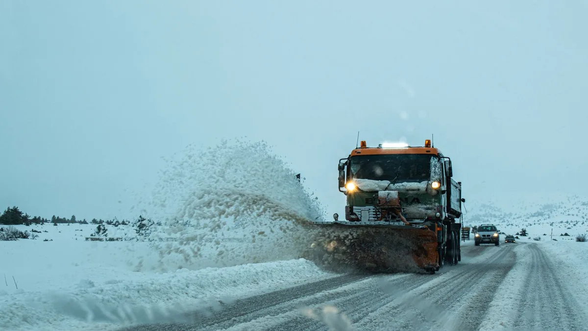 A plow truck at work across an open snow-covered surface