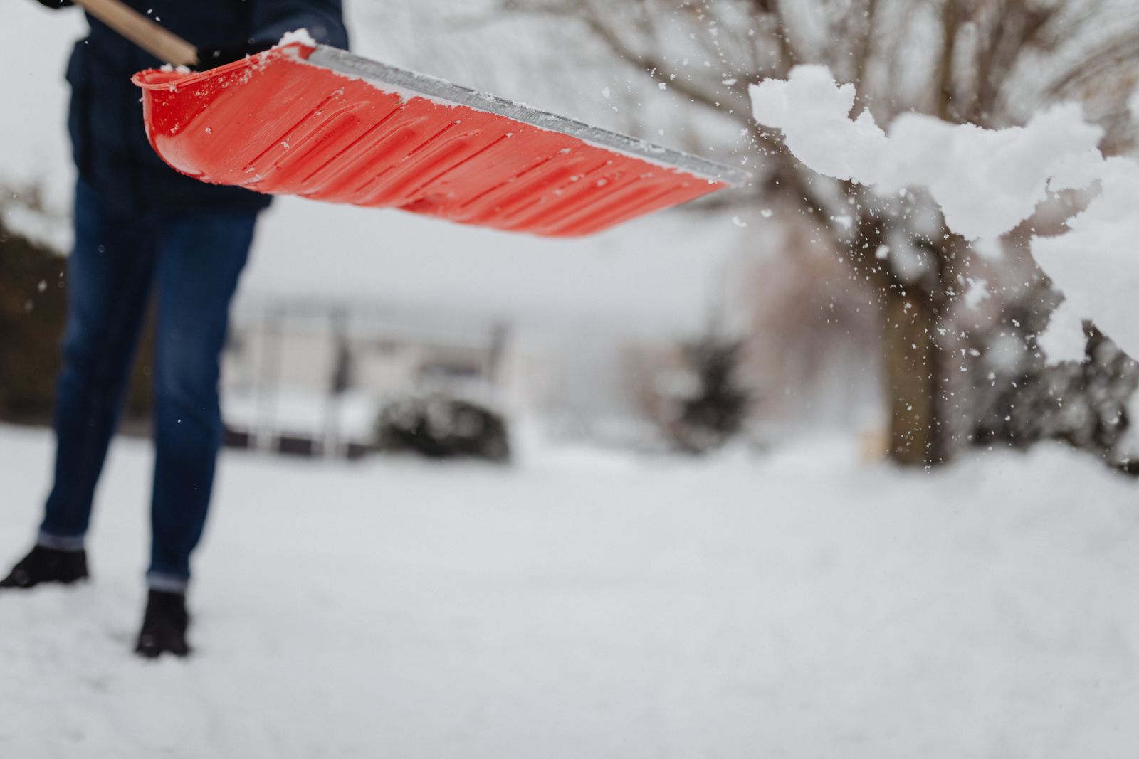 Person shoveling snowy driveway — residential snow removal cost guide